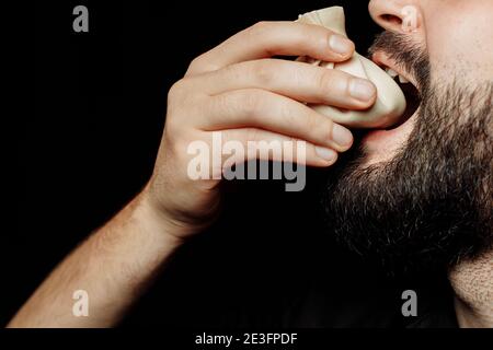 L'uomo bearded sta mangiando emotivamente khinkali. Il khinkali piatto georgiano nazionale. Concetto di pubblicità foto di khinkali Foto Stock