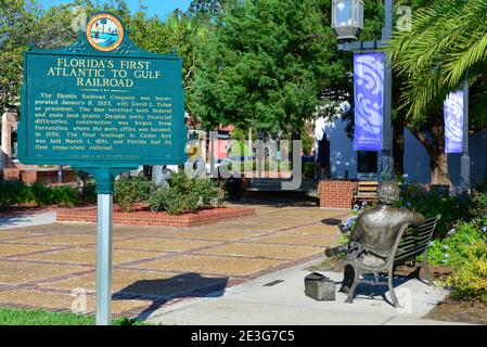 L'Amelia Island Welcome Center, mostra un cartello storico in metallo con vista posteriore di una statua in bronzo seduta del senatore David Yulee, nella storica dow Foto Stock