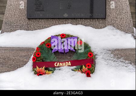 una sola corona parzialmente coperta di neve rimane al memoriale di guerra molto tempo dopo la fine del servizio. Foto Stock