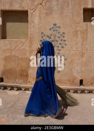 JAIPUR, INDIA - 22 MARZO 2019: Una pulitrice indiana femminile, con scopa di paglia, a piedi in forte ambra Foto Stock