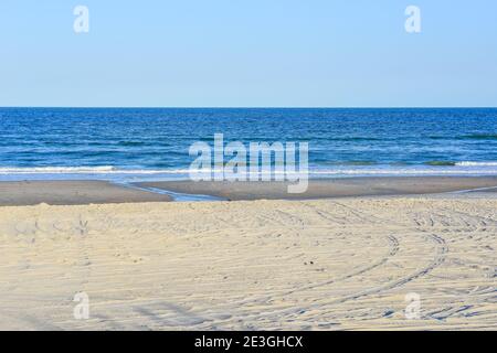 In un ambiente di spiaggia stellato e vuoto, una sdraio gialla si affaccia sull'Oceano Atlantico sulla spiaggia di Fernandina, sull'isola di Amelia, Florida Foto Stock