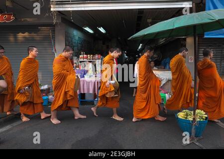 I monaci buddisti novizi con le loro ciotole di elemosina sul loro giro tradizionale di elemosina del mattino (Binta Baat) a Bangkok, Thailandia Foto Stock