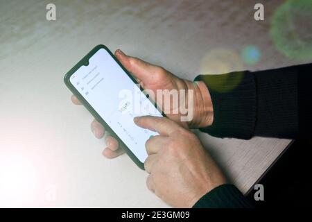 La donna anziana fa clic su un numero di telefono su uno smartphone. Mani di un vecchio. Foto Stock