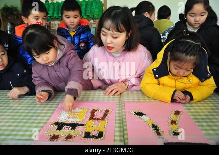 Xuzhou, Cina. 18 gennaio 2021. Per portare avanti la cultura tradizionale, un insegnante sta insegnando ai bambini la conoscenza dei grani al Laba Festival nell'asilo nido di Xuzhou, Jiangsu, Cina il 18 gennaio 2021.(Foto di TPG/cnsphotos) Credit: TopPhoto/Alamy Live News Foto Stock