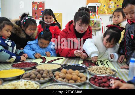 Xuzhou, Cina. 18 gennaio 2021. Per portare avanti la cultura tradizionale, un insegnante sta insegnando ai bambini la conoscenza dei grani al Laba Festival nell'asilo nido di Xuzhou, Jiangsu, Cina il 18 gennaio 2021.(Foto di TPG/cnsphotos) Credit: TopPhoto/Alamy Live News Foto Stock