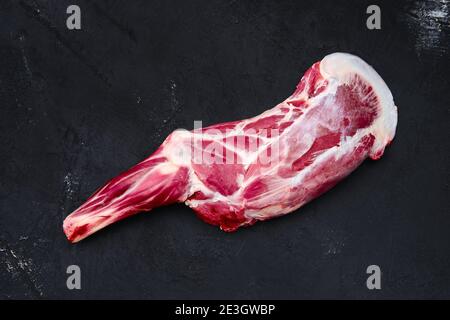 Osso fresco di agnello crudo in su tagliere di legno con erbe e condimento Foto Stock