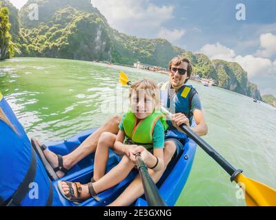 I viaggiatori di mamma, papà e figlio che girano su un kayak nella Baia di ha Long. Vietnam. Viaggio in Asia, emozione di felicità, concetto di vacanza estiva. Viaggiare con Foto Stock