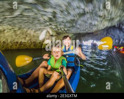 I viaggiatori di mamma, papà e figlio che girano su un kayak nella Baia di ha Long. Vietnam. Viaggio in Asia, emozione di felicità, concetto di vacanza estiva. Viaggiare con Foto Stock