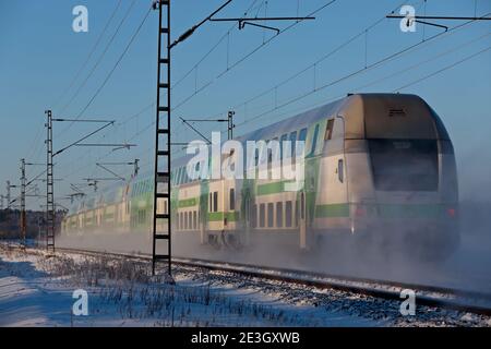 Hameenlinna Finlandia 01/17/2021 treno verde e bianco per passeggeri sulla neve passaggio di polvere Foto Stock