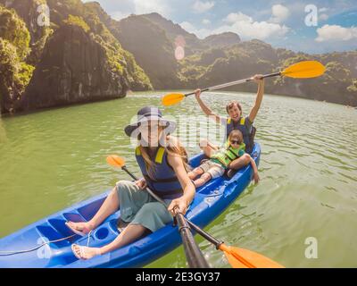 I viaggiatori di mamma, papà e figlio che girano su un kayak nella Baia di ha Long. Vietnam. Viaggio in Asia, emozione di felicità, concetto di vacanza estiva. Viaggiare con Foto Stock