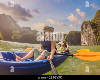 I viaggiatori di mamma, papà e figlio che girano su un kayak nella Baia di ha Long. Vietnam. Viaggio in Asia, emozione di felicità, concetto di vacanza estiva. Viaggiare con Foto Stock