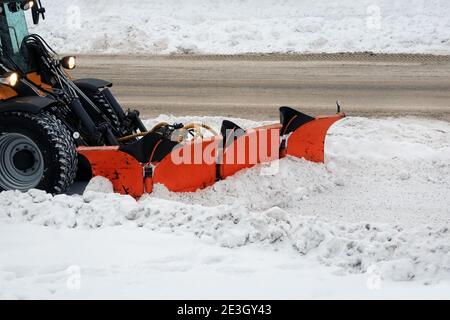 Rimuovere la neve con l'aratro snow snodato dalla strada della città in inverno. Foto Stock