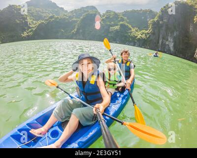 I viaggiatori di mamma, papà e figlio che girano su un kayak nella Baia di ha Long. Vietnam. Viaggio in Asia, emozione di felicità, concetto di vacanza estiva. Viaggiare con Foto Stock