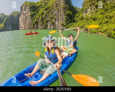 I viaggiatori di mamma, papà e figlio che girano su un kayak nella Baia di ha Long. Vietnam. Viaggio in Asia, emozione di felicità, concetto di vacanza estiva. Viaggiare con Foto Stock