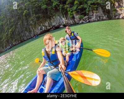 I viaggiatori di mamma, papà e figlio che girano su un kayak nella Baia di ha Long. Vietnam. Viaggio in Asia, emozione di felicità, concetto di vacanza estiva. Viaggiare con Foto Stock