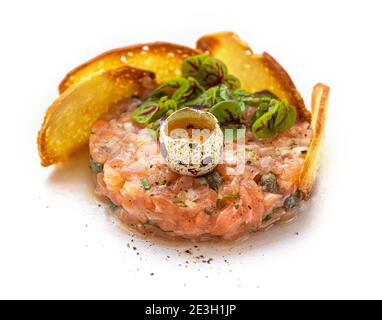 piatto di tartare di salmone con uova crude e pane tostato le sezioni si avvicinano isolate su sfondo bianco Foto Stock