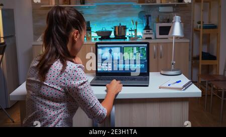Giovane ingegnere del suono che lavora sulle riprese video durante la post-produzione. Creatore di contenuti in home editing su montaggio di film utilizzando software moderni per l'elaborazione a tarda notte. Foto Stock