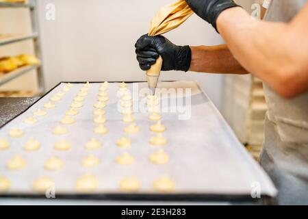 Fuoco selettivo delle mani di uno Chef Pasticceria con pasticceria spremiagrumi nel panificio della pasticceria Foto Stock