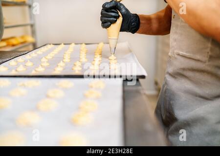 Fuoco selettivo delle mani di uno Chef Pasticceria con pasticceria spremiagrumi nel panificio della pasticceria Foto Stock