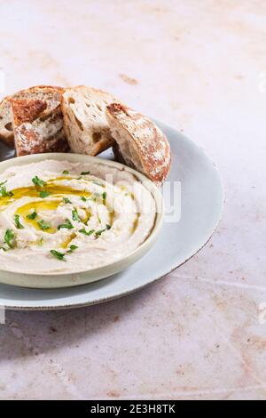 I fagioli cannellini si immergeranno in un piatto condito con olio extra vergine di oliva e prezzemolo tritato, servito con pezzi di pane croccante sul lato. Foto Stock