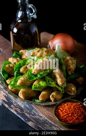 Palle di lenticchie cotte in stile turco. Cibo vegano turco Mercimek Koftesi (lenticchie). Piatti tradizionali locali con lenticchie e bulgaro. Foto Stock