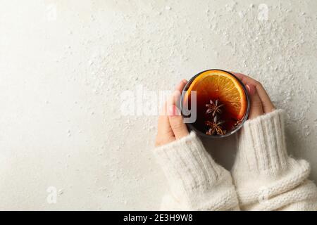 Le mani femminili tengono un bicchiere di VIN brulé su sfondo bianco con neve Foto Stock