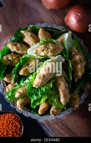 Palle di lenticchie cotte in stile turco. Cibo vegano turco Mercimek Koftesi (lenticchie). Piatti tradizionali locali con lenticchie e bulgaro. Foto Stock