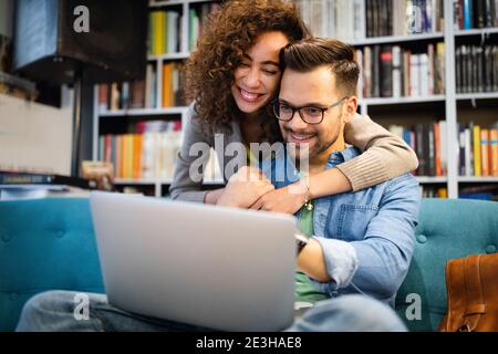 Una coppia si rilassa insieme in un divano con un computer portatile che si diverte. Giovane coppia multirazziale romantica felice Foto Stock