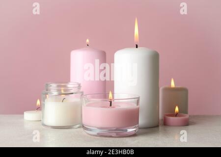 Candele profumate per rilassarsi su un tavolo bianco su sfondo rosa Foto Stock