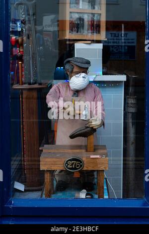 Un manichino nella finestra di un negozio di riparazione scarpe indossa una maschera durante la pandemia covid-19 sulla strada alta di Cheltenham, Inghilterra, il 22 novembre 2020. Foto Stock