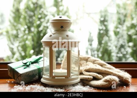 Lanterna, regalo e mittenine su davanzale in legno Foto Stock