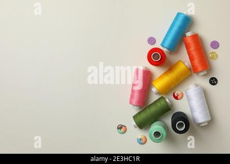 Fili da cucire e bottoni su sfondo bianco, spazio per il testo Foto Stock