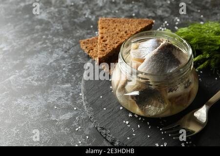 Vassoio con pesce di aringa, sale, pane e aneto su fondo nero di affumicato Foto Stock