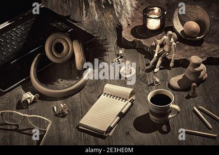 Concetto di scrittura creativa, look retrò. Concetto di vita morta, disposizione su tavolo di legno scuro. Aprire la nota del blocco vuoto. Occhiali, computer portatile con auricolari Foto Stock
