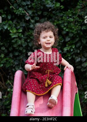 La ragazza del toddler gioca all'aperto nel suo giardino Foto Stock