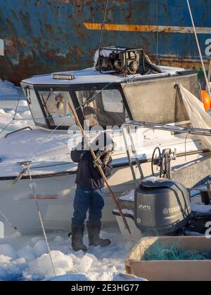 Le piccole imbarcazioni da pesca vengono liberate dal ghiaccio. Inverno nel porto ghiacciato della città Ilulissat sulla riva della baia di Disko. America, Nord America, Greenl Foto Stock