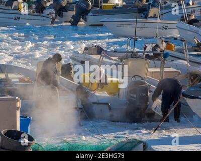 Le piccole imbarcazioni da pesca vengono liberate dal ghiaccio. Inverno nel porto ghiacciato della città Ilulissat sulla riva della baia di Disko. America, Nord America, Greenl Foto Stock