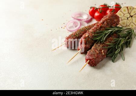 lula kebab crudo, erbe e spezie su fondo testurizzato bianco Foto Stock