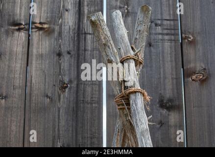 Primo piano di tre pali di legno legati insieme a. forma una tenda Foto Stock