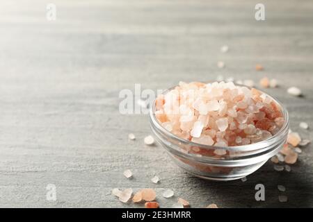 Ciotola di vetro di sale rosa dell'himalaya su tavola grigia Foto Stock