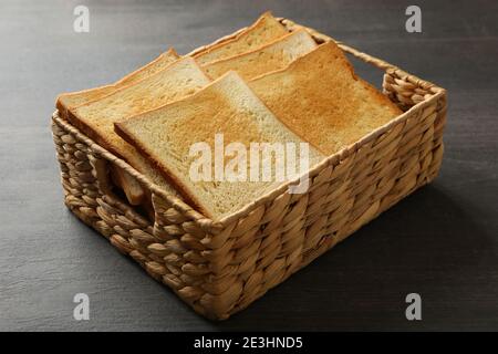 Cestino con pane tostato su sfondo di legno Foto Stock