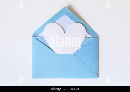 Grande suono bianco su busta blu aperta con grande cuore bianco su sfondo bianco. Lettera d'amore con cuore. Gratitudine a medici e infermieri. San Valentino, M. Foto Stock