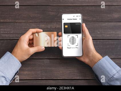Uomo che usa il telefono e la carta di credito che paga in linea indoor, ritagliato Foto Stock