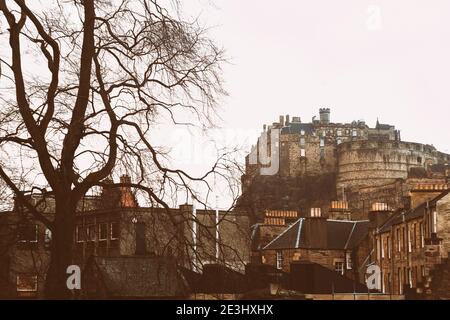 Vista del castello di Edimburgo dal basso con il grande albero nero su la sinistra e gli edifici in primo piano Foto Stock