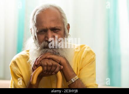 UN ANZIANO SOPPORTATO CHE SI SIEDE TRISTEMENTE E PENSA Foto Stock