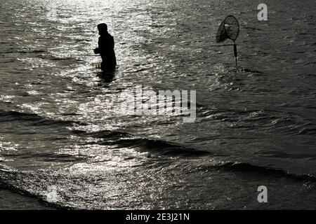 Un solo pescatore Fly pesca silhouette a Grafham Water in Bedfordshire in inverno Foto Stock