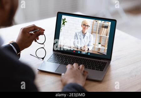 Uomo d'affari nero irriconoscibile che ha videocall con il socio di affari sul laptop Foto Stock