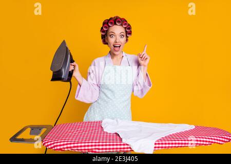 Ritratto di una mamma allegra e glamour con il ferro rivolto verso l'alto soluzione isolato sfondo giallo arancione brillante Foto Stock