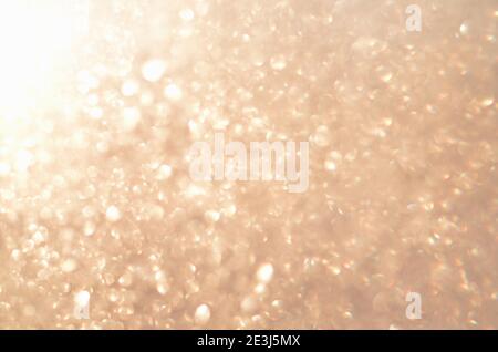 Sfondo glitterato astratto con luce dorata soffusa e sfocata. Immagine sfocata. Foto Stock