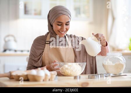 Panificio domestico. Bella signora islamica in hijab preparazione impasto per torta Foto Stock